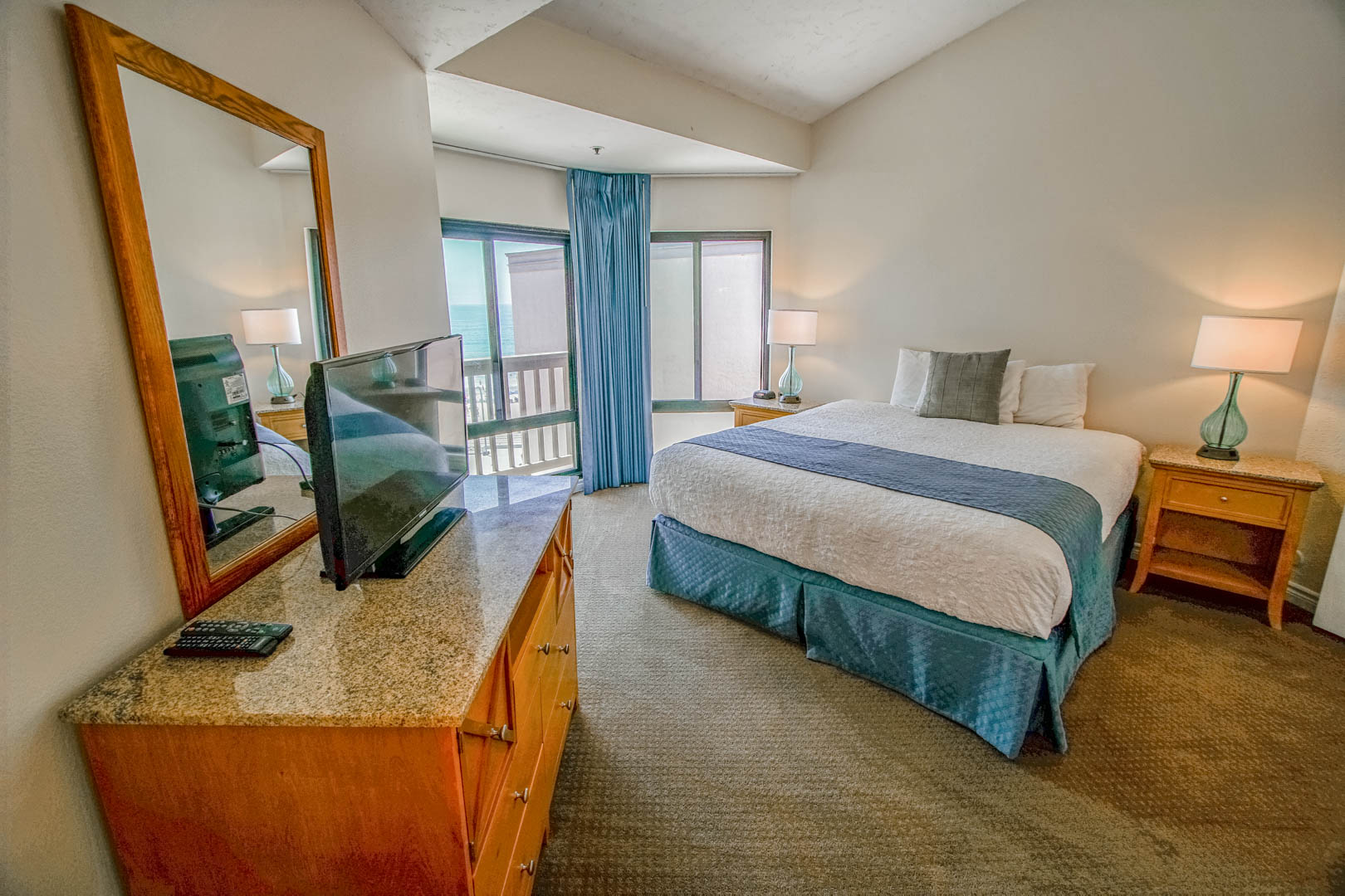 A master bedroom with a balcony overlooking the beach at VRI's See the Sea in San Diego, CA.